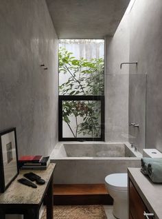 a bathroom with a toilet, sink and bathtub next to a window in the wall