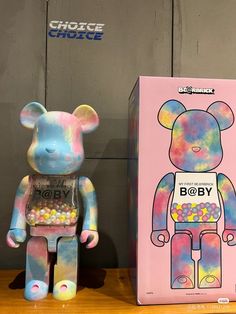 a colorful bear next to a pink box with candy on it and an image of a gummy bear