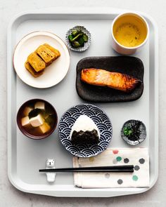 an assortment of food on a tray with chopsticks, sauce and other items