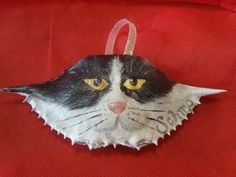 a black and white cat ornament hanging on a red cloth with yellow eyes