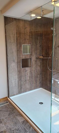 a walk in shower sitting inside of a bathroom next to a tiled floor and walls