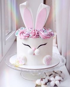 a white cake with pink frosting and bunny ears