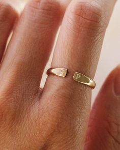 a woman's hand with a gold ring on her finger and the letter p in it