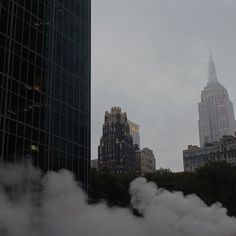 steam rises from the ground in front of skyscrapers