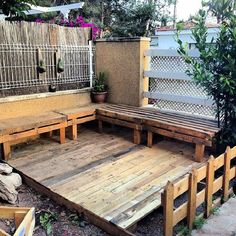 a wooden bench sitting on top of a wooden floor next to a fence and potted plant