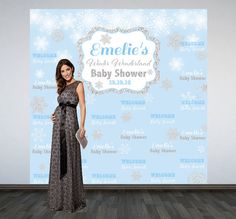 a woman standing in front of a backdrop with snowflakes on it and the name emelie's baby shower