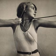 an old black and white photo of a woman holding a bow