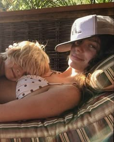 two women and a child are laying on a hammock in the sun together