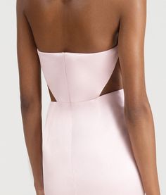 the back of a woman wearing a light pink dress with cutouts on the sides