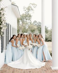 a group of bridesmaids posing for a photo in front of a white house