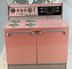 a pink stove top oven sitting on top of a doily