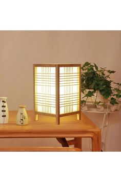 a wooden table topped with two vases and a lit up screen on top of it