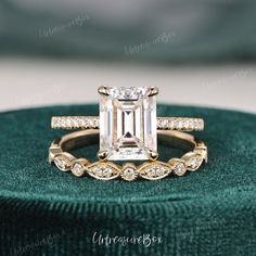 an emerald colored diamond engagement ring set on top of a green velvet cushioned box