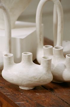 several white vases sitting on top of a wooden table