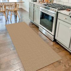 a kitchen area with an oven, stove and dining room table in the back ground