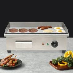 an electric griddle grill with eggs, sausages and other food items on it