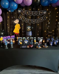 a birthday party with balloons and decorations on the table in front of a black backdrop