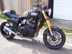 a black motorcycle parked in front of a garage with a red stripe on the tire