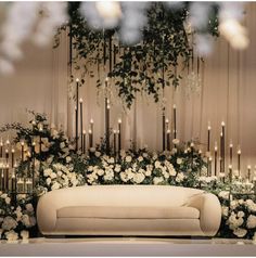 a white couch sitting in front of a bunch of candles and flowers on a wall