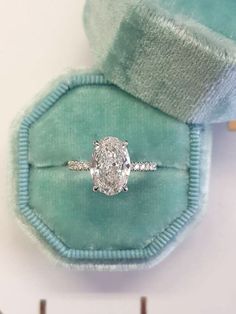 an oval diamond ring sits in a velvet case