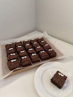 there are many brownies with eyes on them sitting on the table next to a plate