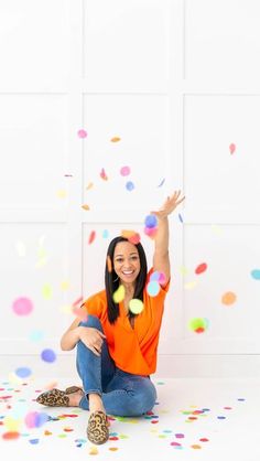 a woman sitting on the floor with confetti in front of her and smiling