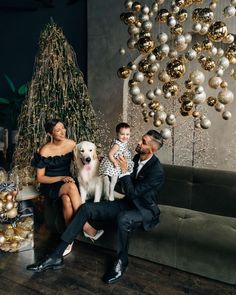 a man, woman and child sitting on a couch with a dog