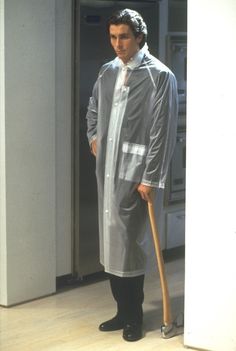 a man standing in front of an open refrigerator wearing a raincoat and holding a cane