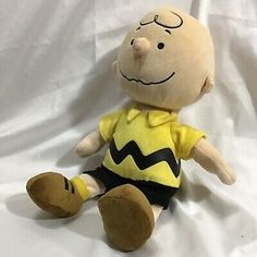 a stuffed toy with a yellow shirt and black pants on it's legs, sitting on a white sheet