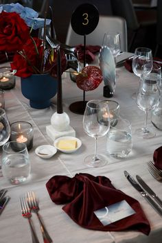 the table is set with wine glasses, silverware and candles for an elegant dinner