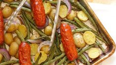 two trays filled with potatoes, green beans and hot dogs on top of them