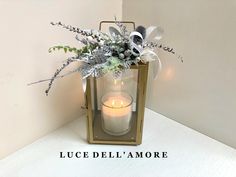 a candle that is sitting next to a vase with flowers on it and the words luce dell amore above it