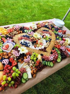 a table topped with lots of different types of food on top of grass covered ground