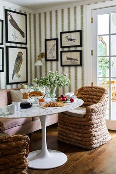 a dining room with pictures on the wall and table in front of it, along with wicker chairs