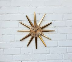 a clock that is on the side of a brick wall in front of a white brick wall