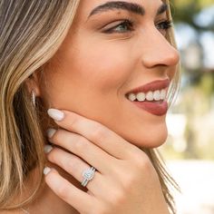 a woman wearing a diamond ring with her hand on her shoulder, smiling at the camera