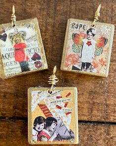 three square pendants with pictures on them sitting on top of a wooden table next to each other