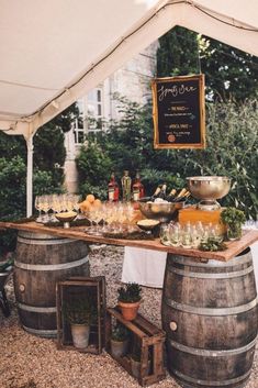 an outdoor bar set up with wine glasses and bottles on top of wooden barrels under a tent