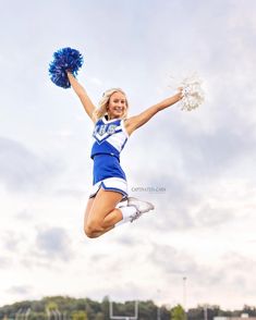 a cheerleader jumping in the air with her pom poms