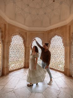 a man and woman dancing in an ornate room with arched windowed arches on the ceiling