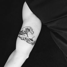 a black and white photo of a wave tattoo on the arm