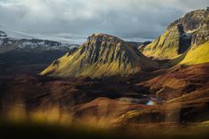 the mountains are covered in green and brown grass, with a lake at the bottom