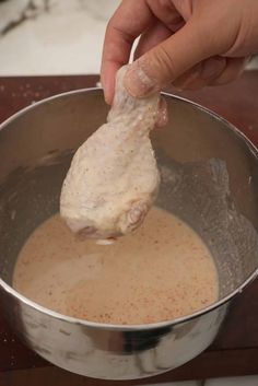 someone is dipping something into a sauce in a metal bowl