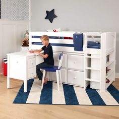 a young boy sitting at a desk in front of a white bunk bed with drawers