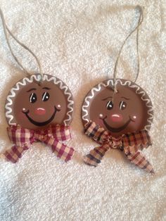 two christmas ornaments with faces on them are hanging from twine strings, one is brown and the other is red