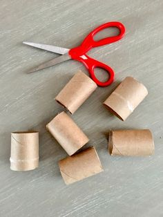 several rolls of toilet paper next to a pair of red scissors on a table top