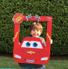 a young boy holding up a cardboard car