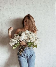 a woman with long hair holding flowers in her hands