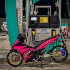 a pink motorcycle parked next to a gas pump