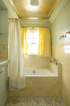 a bathroom with yellow curtains and white fixtures